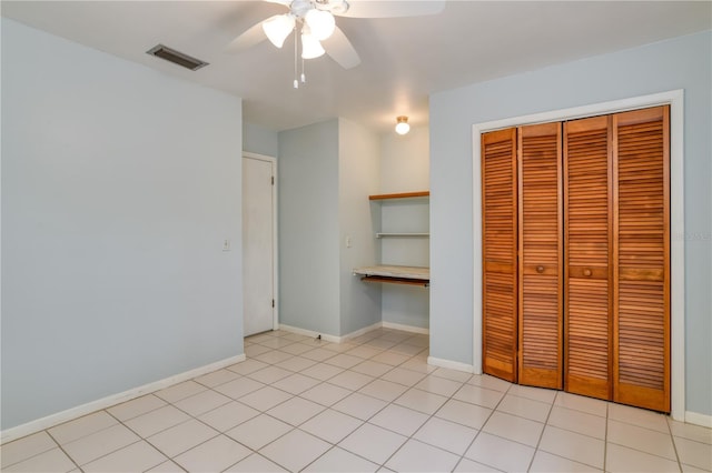 unfurnished bedroom with ceiling fan, light tile patterned flooring, and a closet