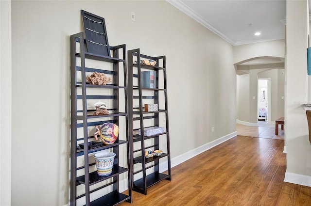 hall featuring arched walkways, ornamental molding, wood finished floors, and baseboards