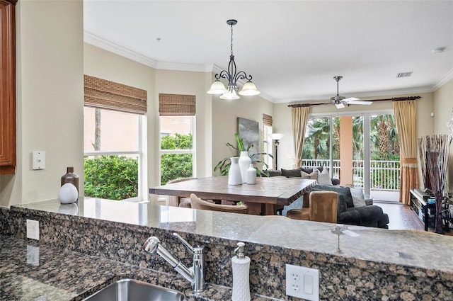 kitchen featuring a sink, visible vents, ornamental molding, dark stone counters, and pendant lighting