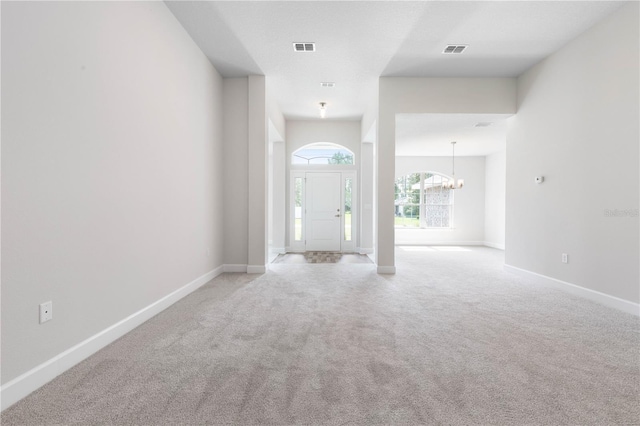 entrance foyer featuring light carpet and an inviting chandelier