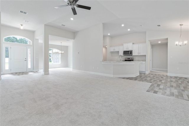 unfurnished living room with sink, light colored carpet, and ceiling fan with notable chandelier