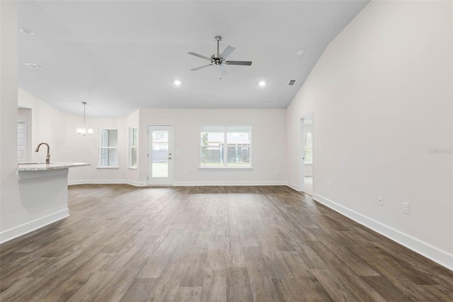 unfurnished living room with baseboards, dark wood finished floors, recessed lighting, a sink, and ceiling fan with notable chandelier