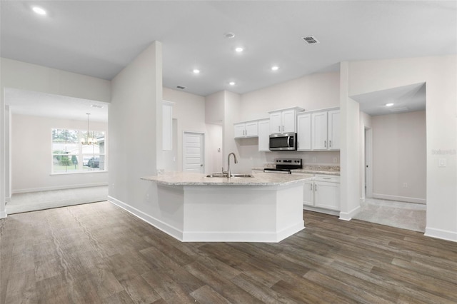 kitchen with dark wood finished floors, a peninsula, a sink, white cabinets, and appliances with stainless steel finishes