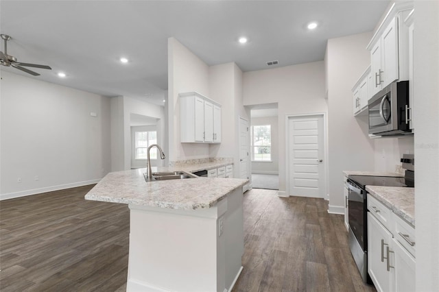 kitchen with dark wood-type flooring, a sink, white cabinetry, stainless steel appliances, and a peninsula