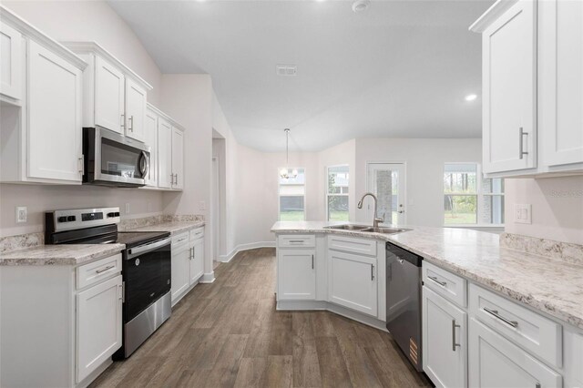 kitchen with dark wood-type flooring, appliances with stainless steel finishes, a peninsula, white cabinets, and a sink