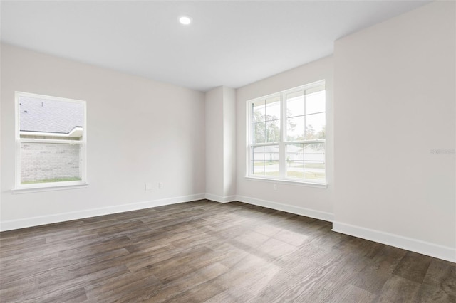 empty room with dark wood-type flooring, recessed lighting, and baseboards