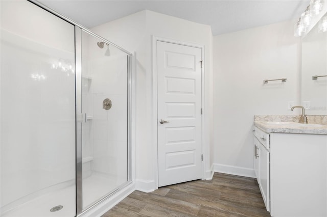 bathroom featuring vanity, a shower stall, wood finished floors, and baseboards