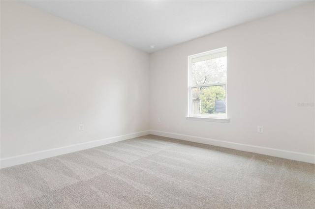 unfurnished room featuring light colored carpet and baseboards