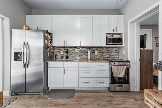 kitchen featuring white cabinetry, sink, stainless steel appliances, stone countertops, and decorative backsplash