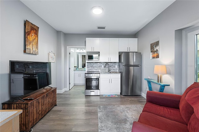 kitchen featuring decorative backsplash, white cabinetry, sink, and stainless steel appliances