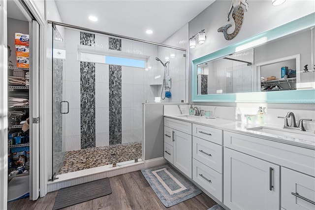 bathroom with a shower with shower door, wood-type flooring, and vanity