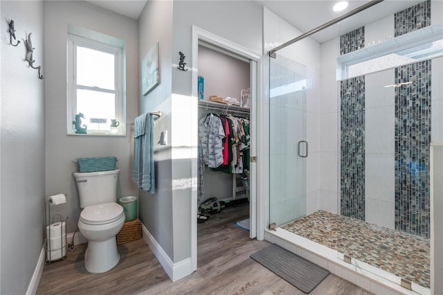 bathroom featuring hardwood / wood-style flooring, toilet, and a shower with shower door