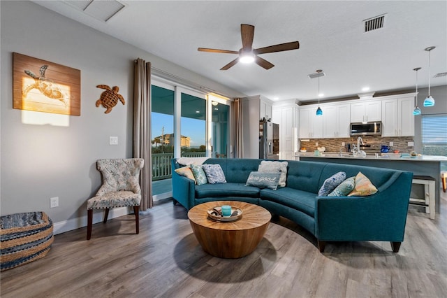 living room featuring hardwood / wood-style floors, ceiling fan, and sink