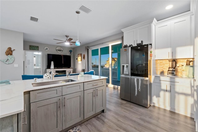 kitchen featuring backsplash, ceiling fan, sink, white cabinets, and stainless steel fridge with ice dispenser