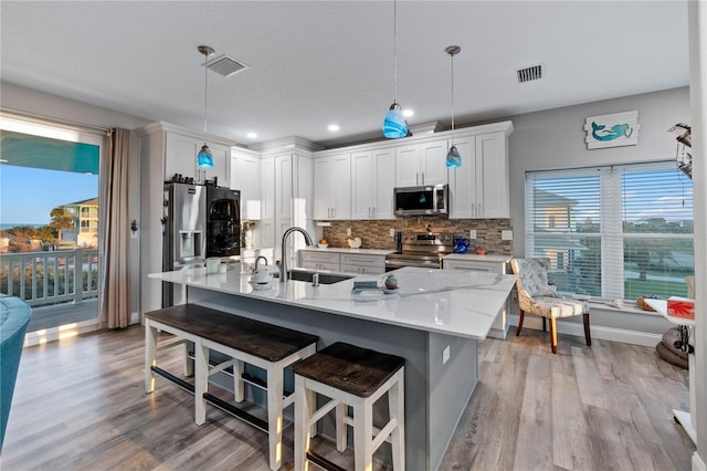 kitchen with white cabinetry, sink, decorative light fixtures, appliances with stainless steel finishes, and light wood-type flooring