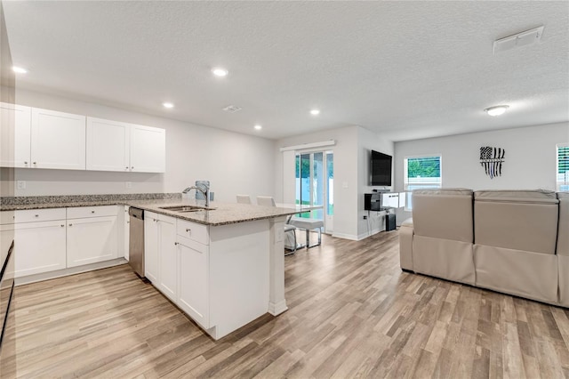 kitchen featuring sink, light stone counters, kitchen peninsula, white cabinets, and light wood-type flooring