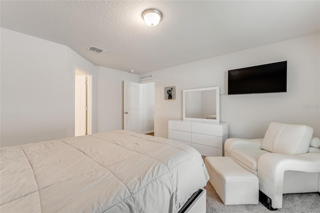 bedroom with a textured ceiling and light carpet