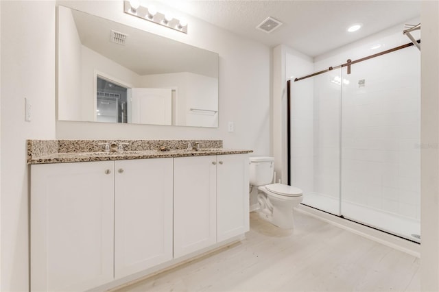 bathroom featuring wood-type flooring, vanity, toilet, and walk in shower