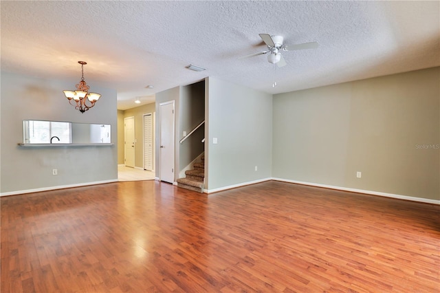 unfurnished living room with ceiling fan with notable chandelier, a textured ceiling, and hardwood / wood-style flooring