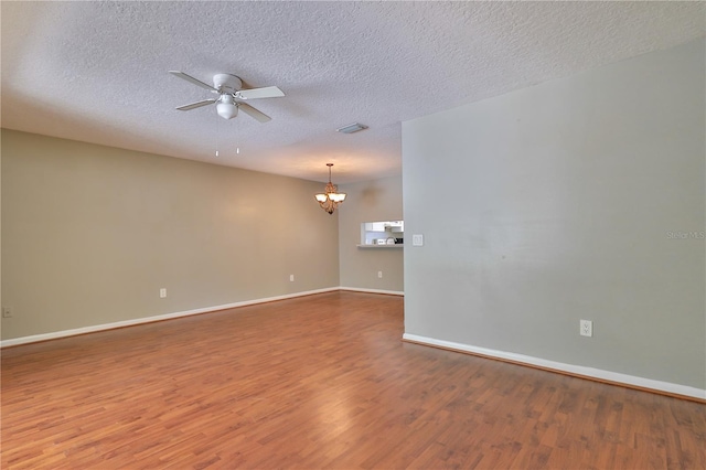 spare room with ceiling fan with notable chandelier, hardwood / wood-style floors, and a textured ceiling