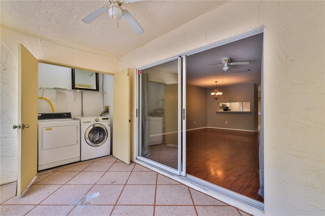 laundry room featuring ceiling fan with notable chandelier, a textured ceiling, light wood-type flooring, and washing machine and dryer