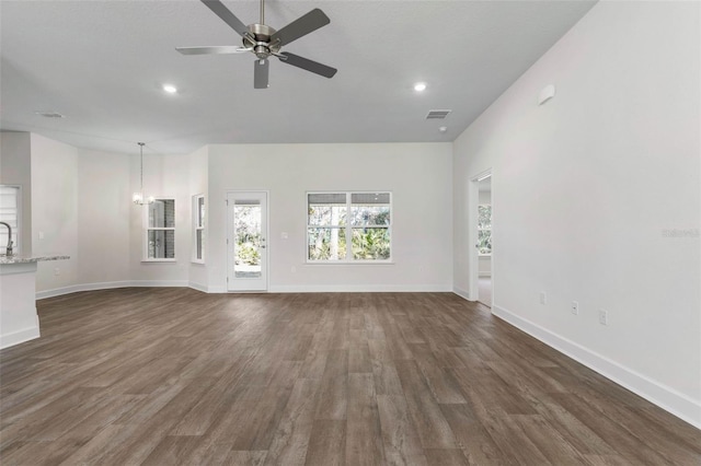 unfurnished living room featuring dark hardwood / wood-style flooring, ceiling fan with notable chandelier, and sink