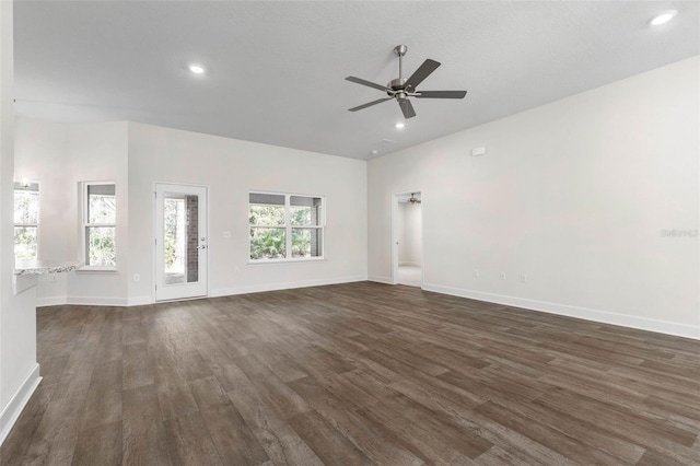 unfurnished living room with ceiling fan, a wealth of natural light, and dark hardwood / wood-style flooring