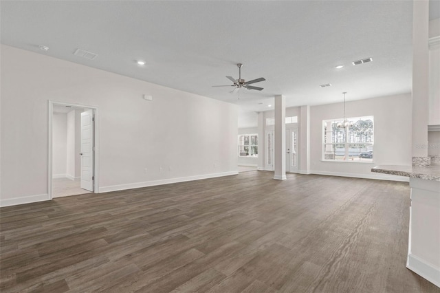 unfurnished living room with dark wood-type flooring and ceiling fan with notable chandelier