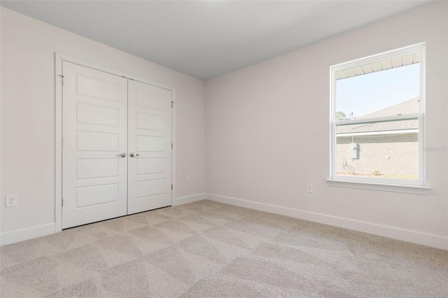 unfurnished bedroom featuring light carpet and a closet