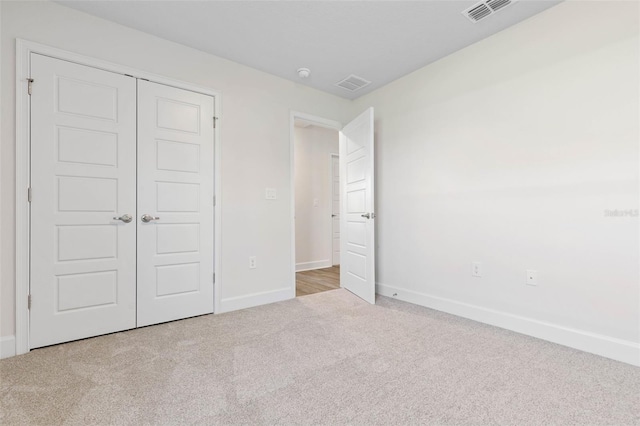 unfurnished bedroom with light carpet and a closet