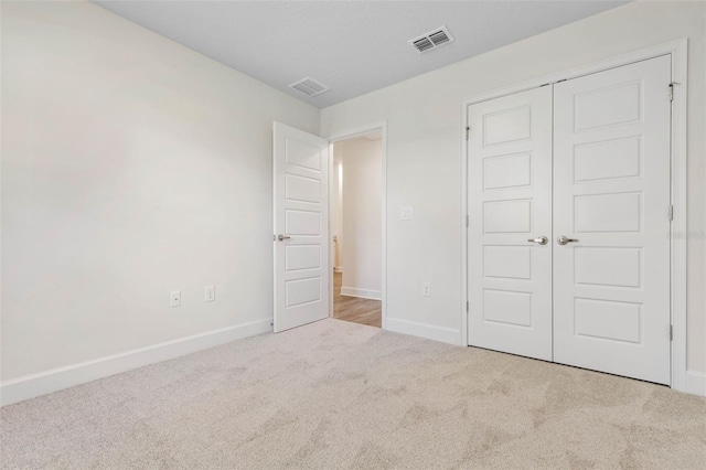 unfurnished bedroom featuring light carpet and a closet