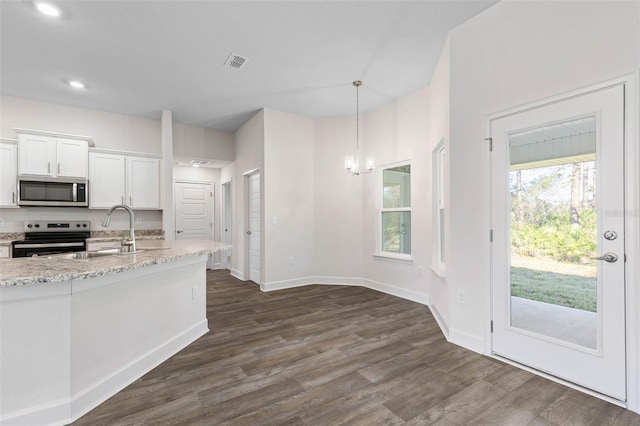 kitchen with appliances with stainless steel finishes, decorative light fixtures, dark wood-type flooring, white cabinetry, and light stone counters