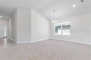 spare room featuring carpet floors, vaulted ceiling, and an inviting chandelier