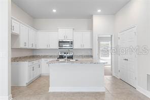 kitchen featuring white cabinets, appliances with stainless steel finishes, and an island with sink