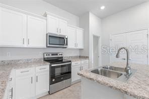 kitchen with light stone countertops, white cabinetry, sink, and appliances with stainless steel finishes