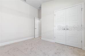 unfurnished bedroom with light colored carpet and a closet