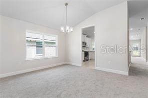 empty room featuring light colored carpet, lofted ceiling, and an inviting chandelier