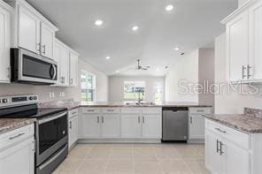 kitchen featuring ceiling fan, sink, stainless steel appliances, kitchen peninsula, and white cabinets