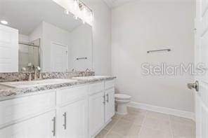 bathroom featuring toilet, vanity, tile patterned floors, and an enclosed shower