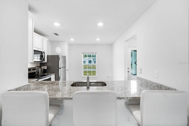 kitchen featuring white cabinets, sink, light stone countertops, and stainless steel appliances