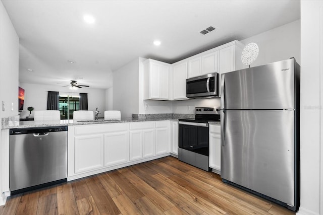 kitchen featuring light stone countertops, appliances with stainless steel finishes, dark hardwood / wood-style flooring, sink, and white cabinets