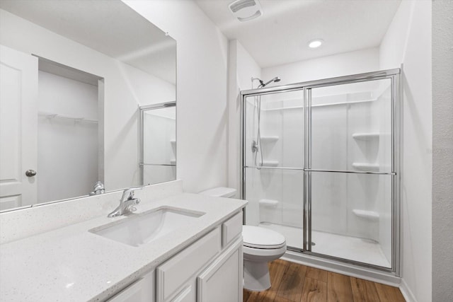 bathroom featuring vanity, toilet, wood-type flooring, and a shower with door