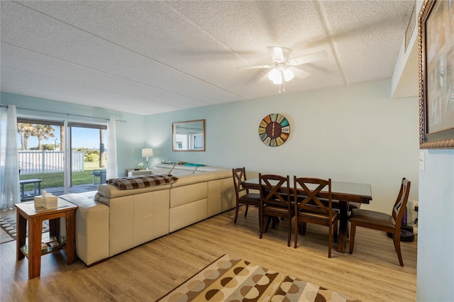 living room featuring ceiling fan, light hardwood / wood-style floors, and a textured ceiling