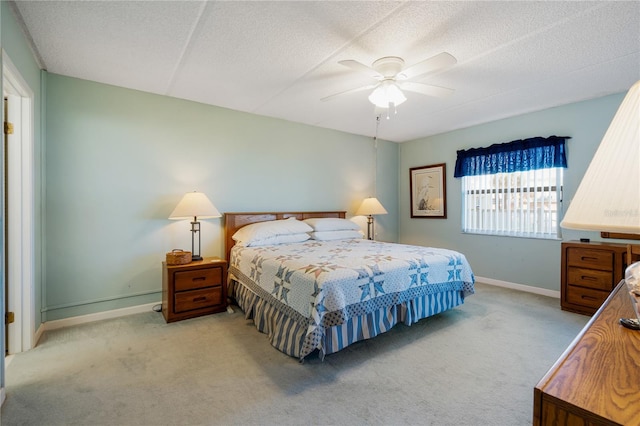 carpeted bedroom featuring ceiling fan and a textured ceiling