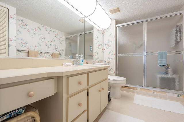 bathroom featuring a shower with door, vanity, a textured ceiling, and toilet