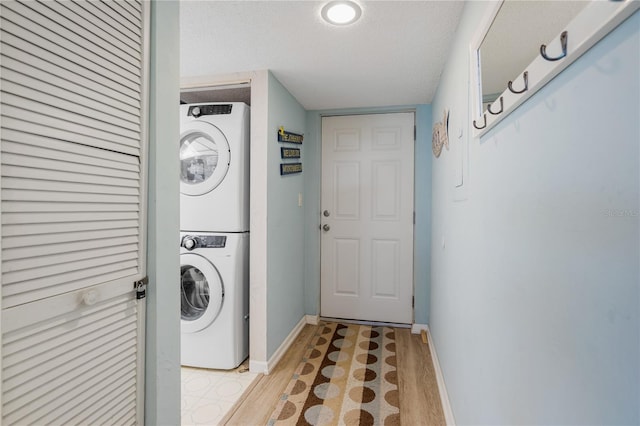 2294 Ocean Shore Blvd Unit 1020, Ormond Beach, FL 32176 - laundry area with stacked washer and clothes dryer, baseboards, light wood-style flooring, and a textured ceiling