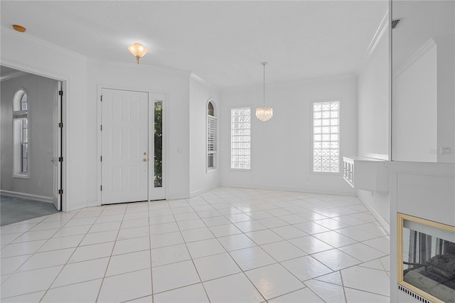 foyer entrance with an inviting chandelier, light tile patterned floors, and crown molding