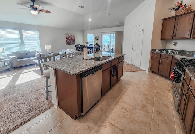 kitchen with lofted ceiling, light carpet, a center island with sink, sink, and stainless steel appliances