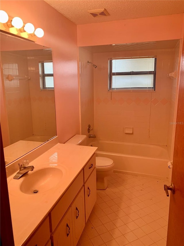 full bathroom featuring tiled shower / bath combo, tile patterned floors, a textured ceiling, toilet, and vanity