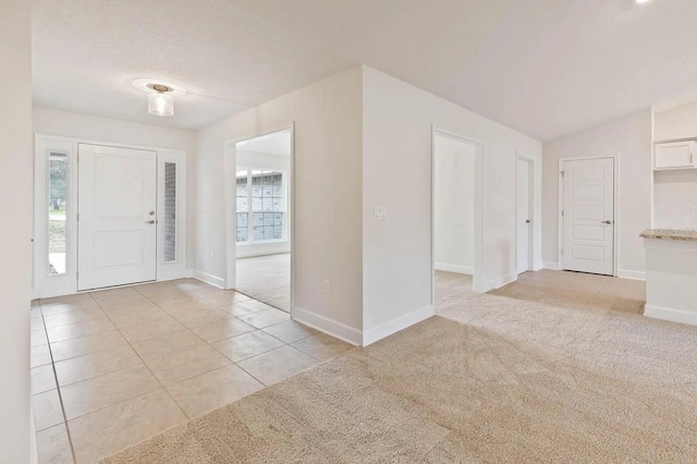 carpeted foyer entrance featuring lofted ceiling and a healthy amount of sunlight